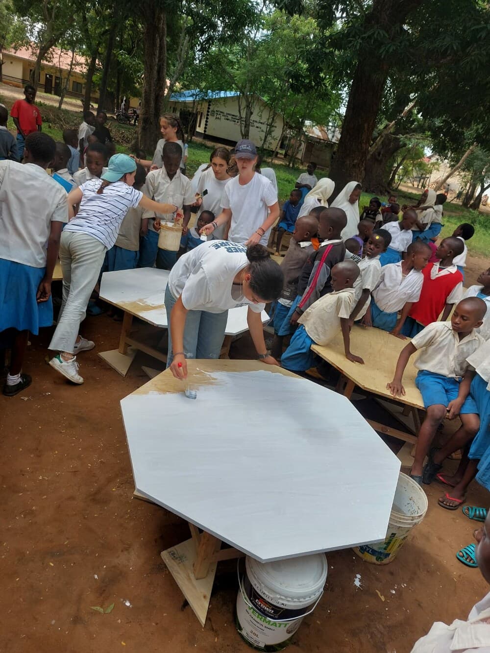 Voluntàries i estudiants pintant noves taules escolars a Shariani